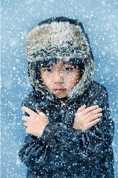 a young boy clutching his shoulders in the snow