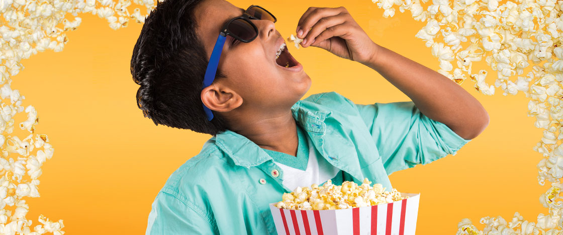 A boy dropping popcorn in his mouth