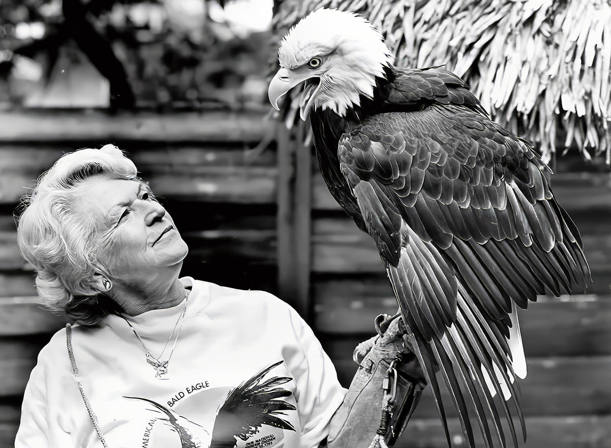 Black & white photo of a person posing with bald eagle